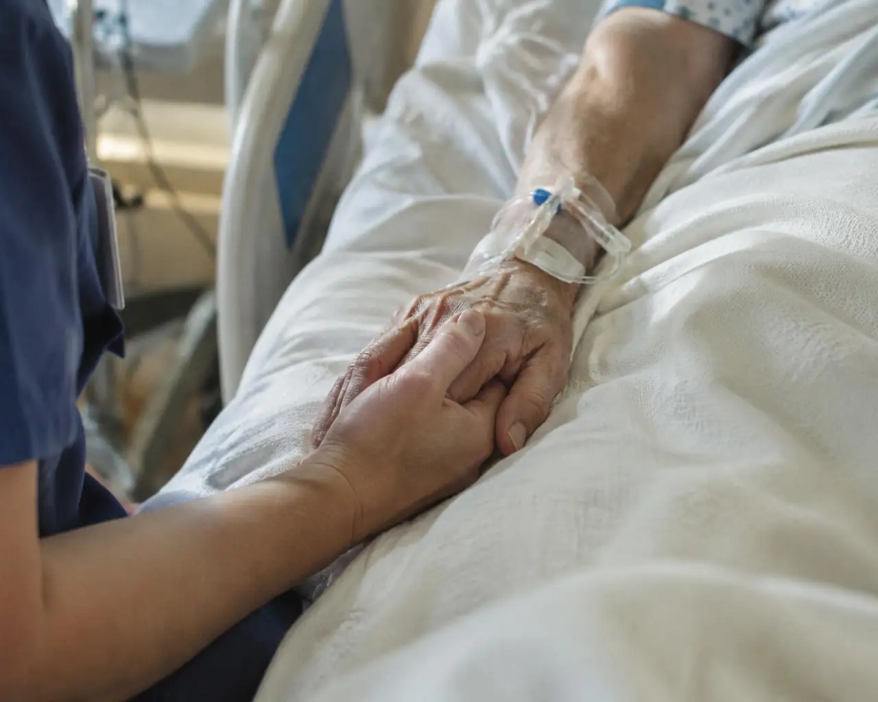 A nurse holding a patient's hand